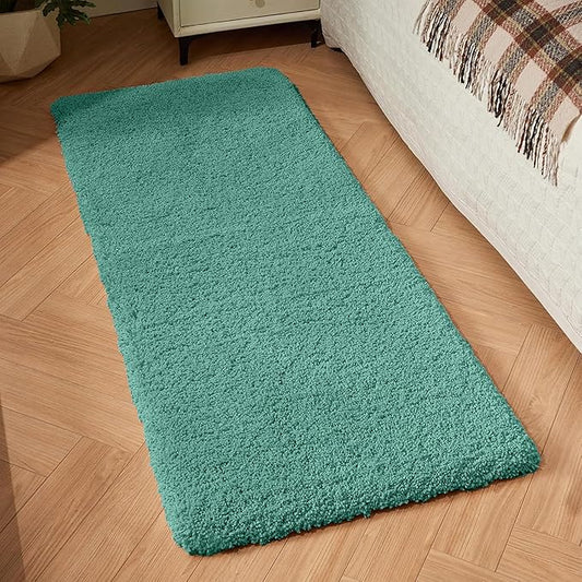 Teal bathmat runner on wooden bedroom floor beside bed, soft and textured surface.