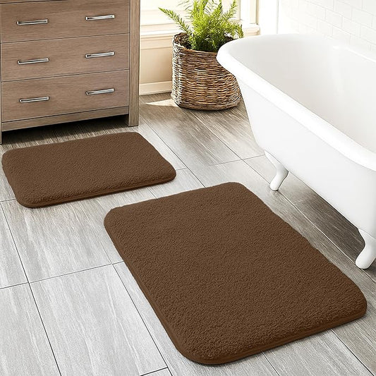 Set of two brown bathmats on tiled bathroom floor near bathtub and wooden cabinet