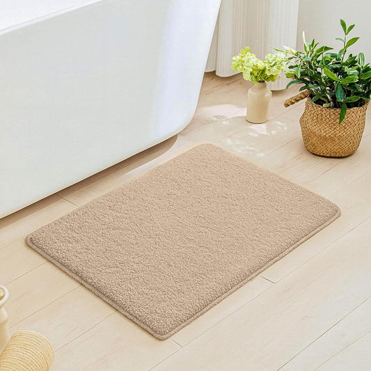 Soft beige bathmat on wooden bathroom floor near white bathtub and potted plants