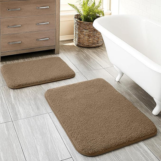Set of two brown bathmats on bathroom floor beside white tub and wooden cabinet