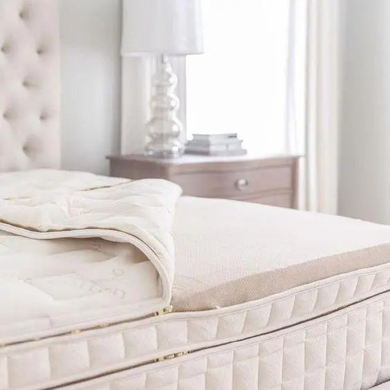Plush bed with cream mattress, soft quilt, and bedside table in a bright bedroom