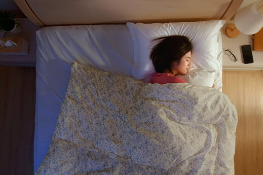 Woman sleeping under a floral dohar blanket on a bed with white pillow and bedsheet
