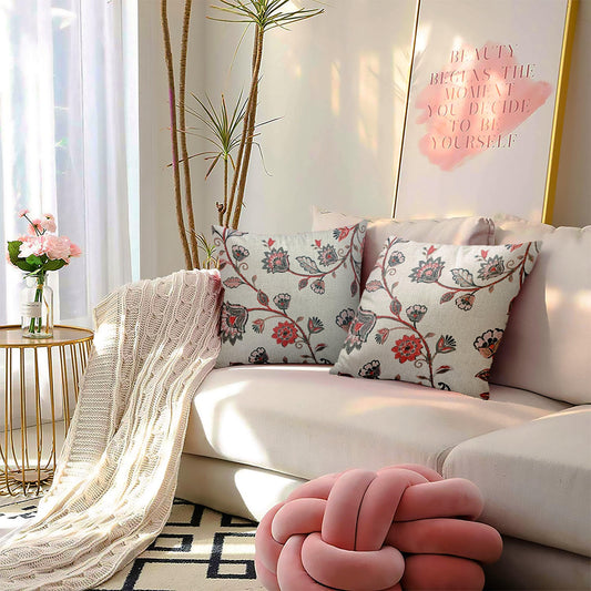 Modern living room with floral print pillows, beige knit throw, and soft pink knot cushion on a cream sofa