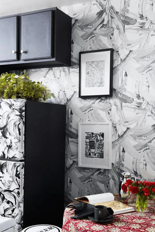 Modern kitchen with black cabinets, abstract patterned wallpaper, and red floral tablecloth