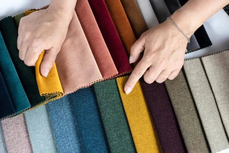 Hands selecting colorful fabric swatches for home textiles or bedding shopping