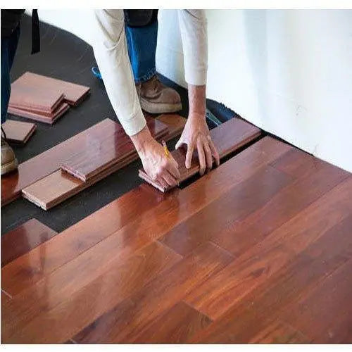 Worker installing wooden flooring panels on a residential interior floor