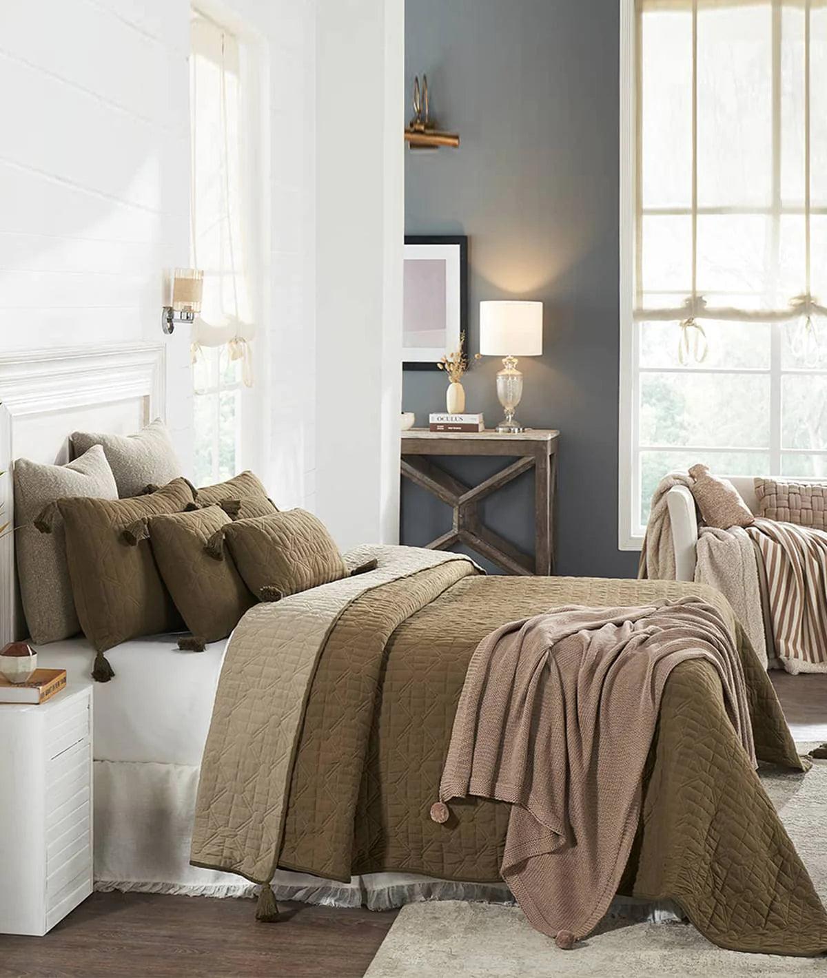Cozy bedroom with olive green quilted bedspread, matching pillows, and soft throw blanket