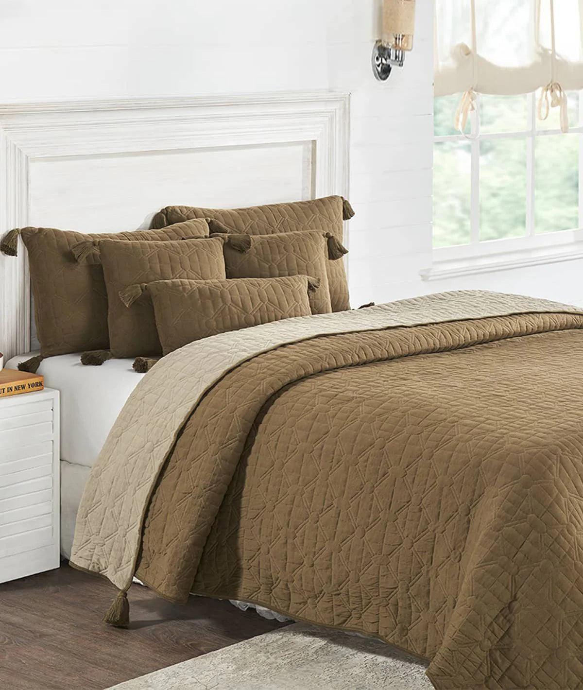 Brown quilted comforter set with matching pillows and tassels on a white bed