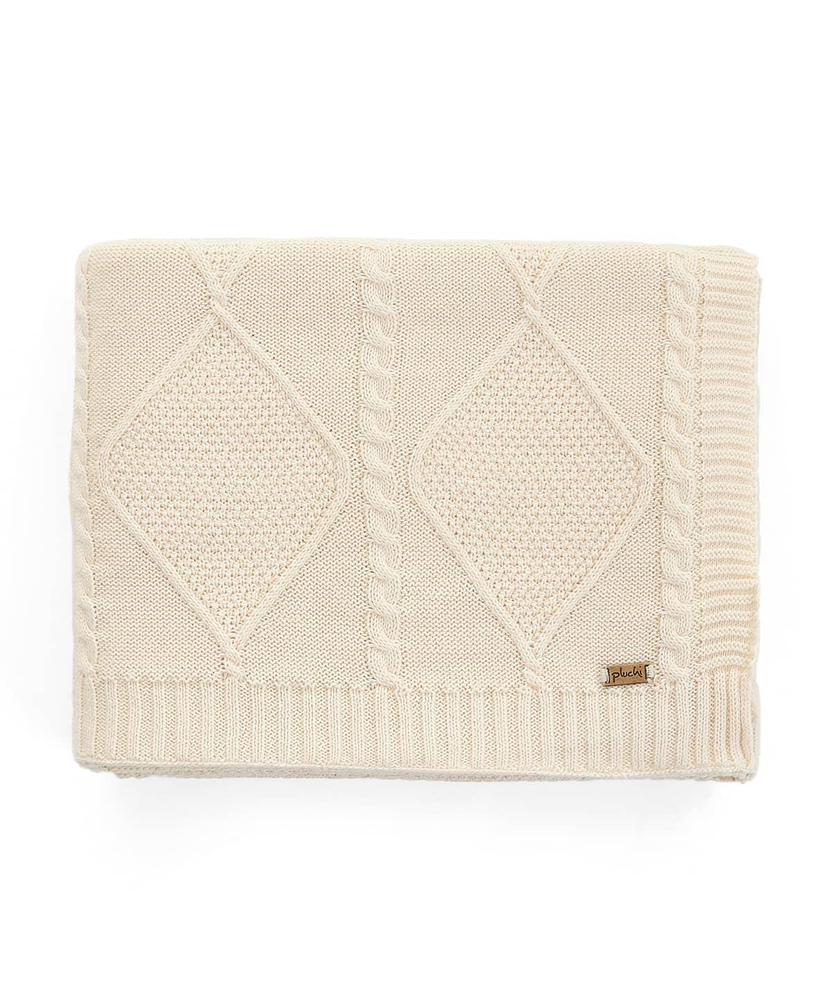 Folded cream knitted blanket with diamond and cable knit pattern on a white background