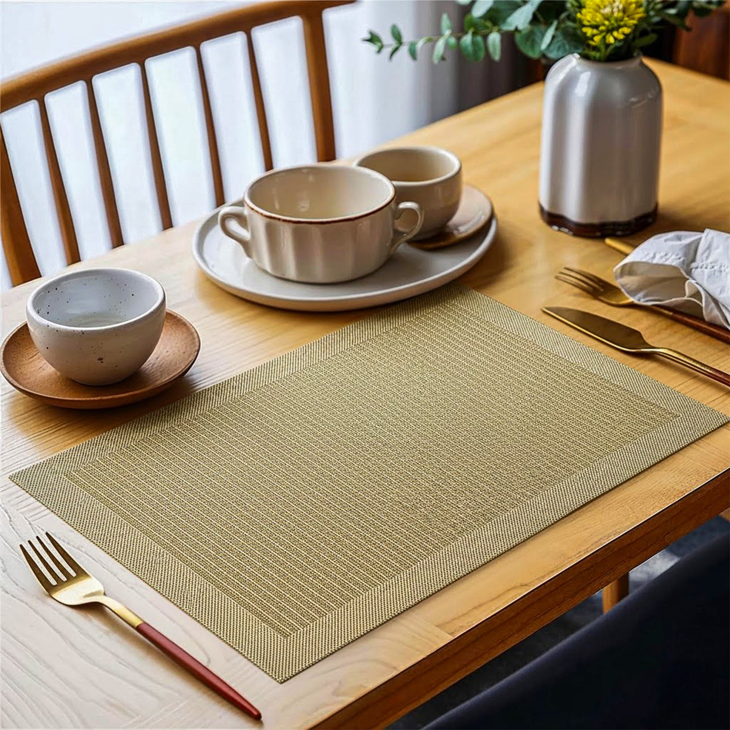 Beige textured placemat on dining table with ceramic dishes and gold cutlery
