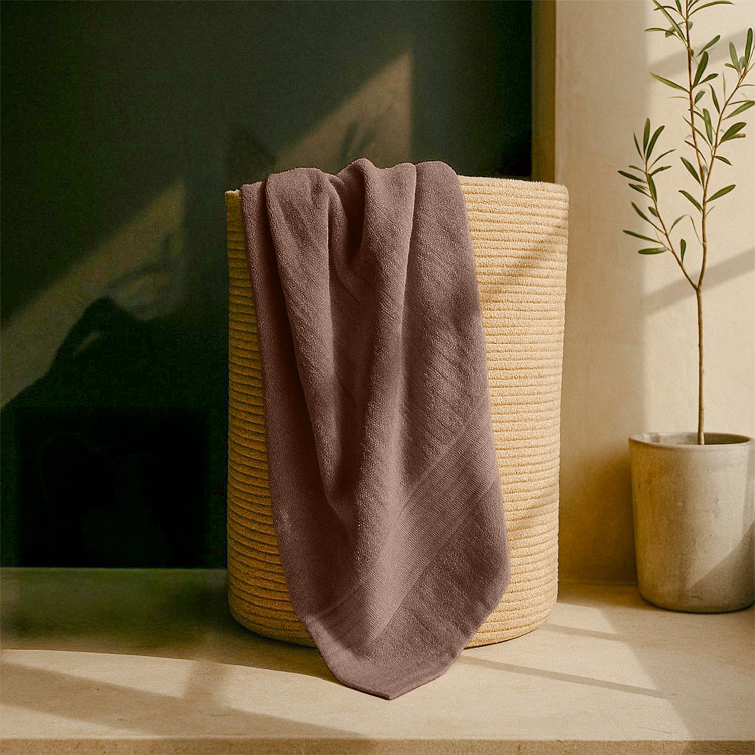 Brown bath towel draped over a woven basket in a sunlit bathroom setting