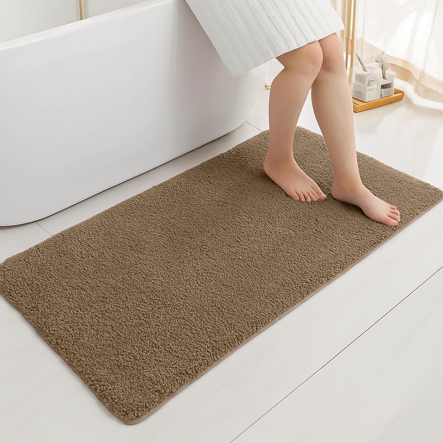 Brown bathmat on bathroom floor with person stepping out of bathtub
