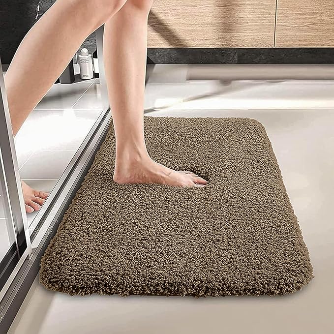 Person stepping onto a soft brown bathroom bathmat on a tiled floor