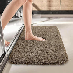 Person stepping onto a soft brown bathroom bathmat on a tiled floor