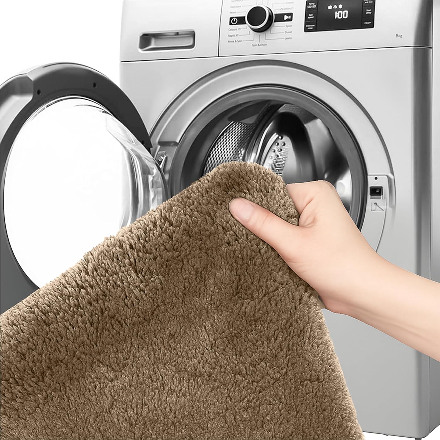 Hand holding soft brown bathmat in front of washing machine, washable bathroom rug