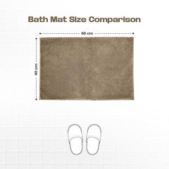 Brown bath mat measuring 60x40 cm on white tile, size comparison with slippers.