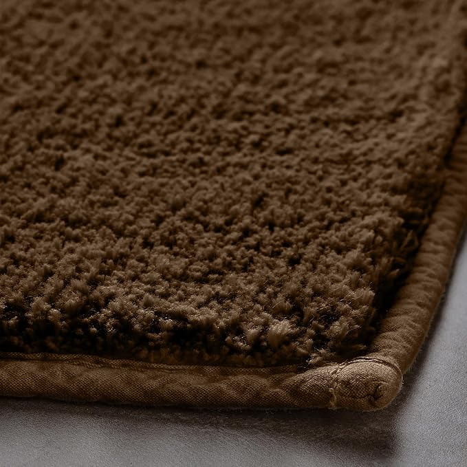 Close-up of a brown textured bathmat with soft plush surface and stitched edge