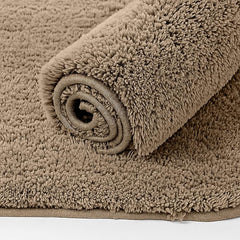 Rolled beige bathmat with soft, plush texture on a matching background