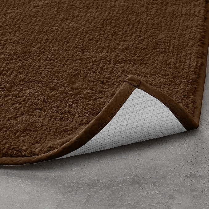 Brown textured bathmat with non-slip white backing on a grey floor