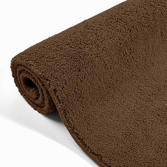 Rolled brown bathmat with soft, textured surface for bathroom decor