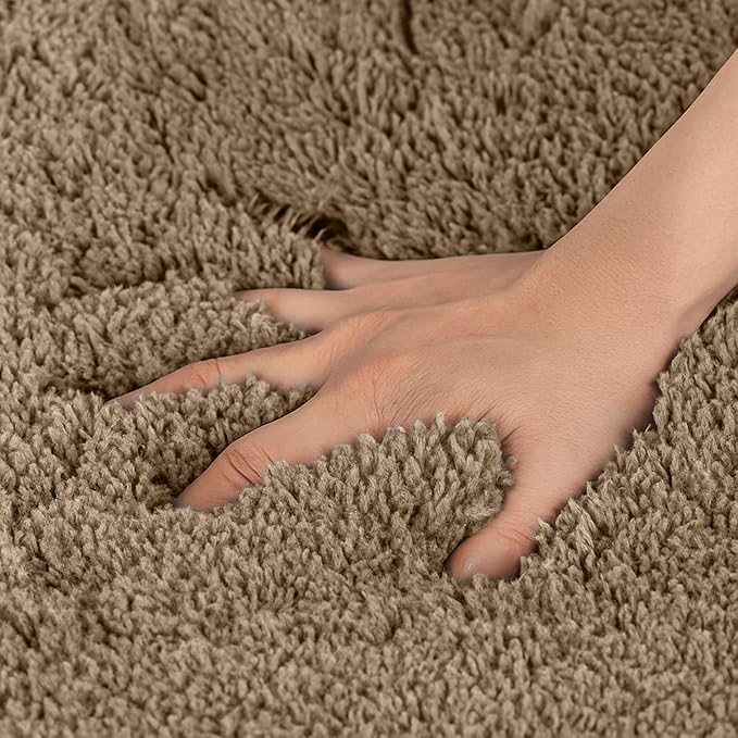Hand pressing into a soft, thick beige bathmat showing plush texture