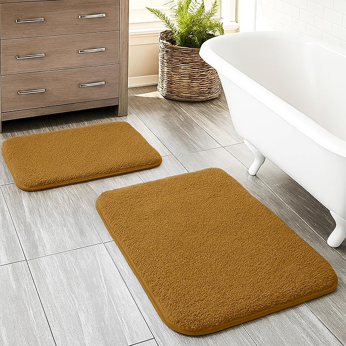 Soft brown bathmats on tiled bathroom floor near bathtub and cabinet