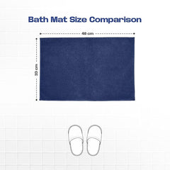 Navy blue bath mat measuring 48 cm by 33 cm on tile, size comparison with slippers.