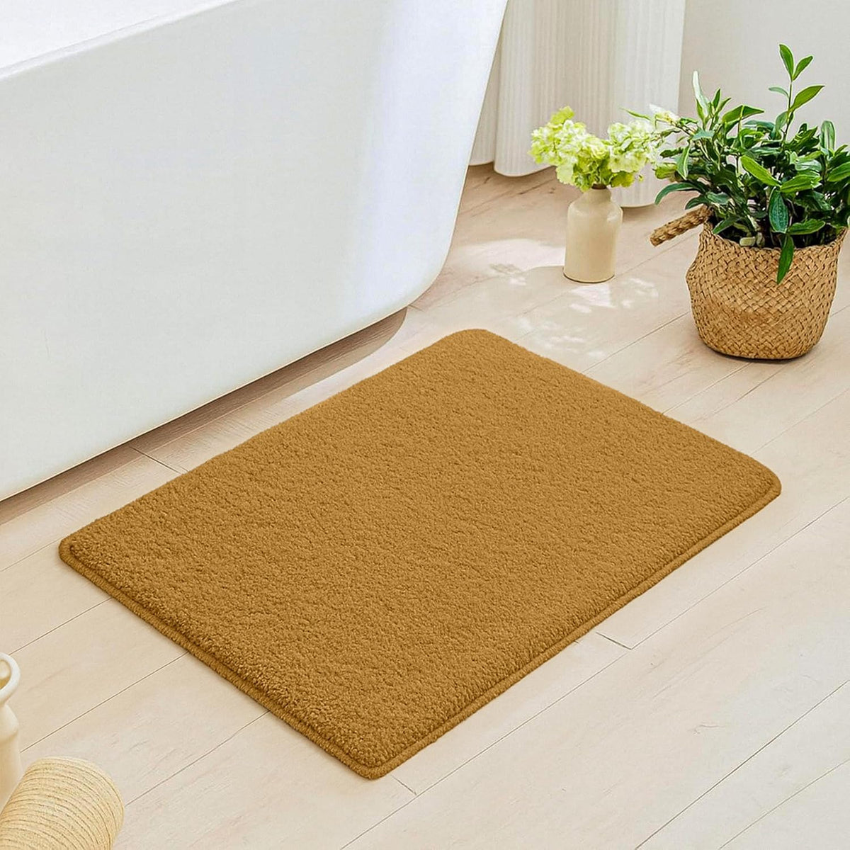 Brown bathmat on light bathroom floor near bathtub and decorative plants