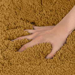 Hand pressing into soft, brown shaggy bathmat, highlighting plush bathroom rug texture