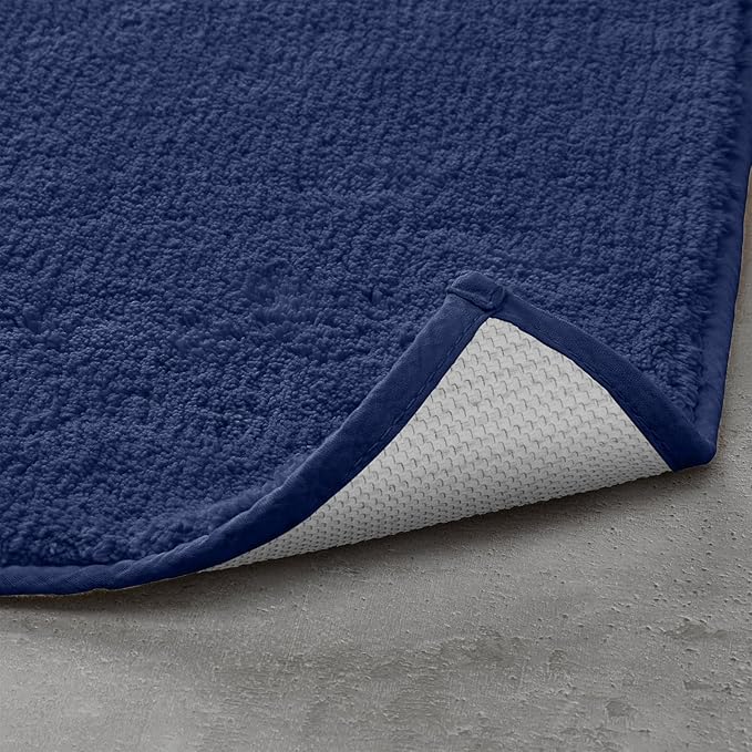 Navy blue textured bathmat with non-slip backing on a grey bathroom floor
