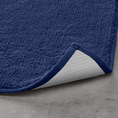 Navy blue textured bathmat with non-slip backing on a grey bathroom floor