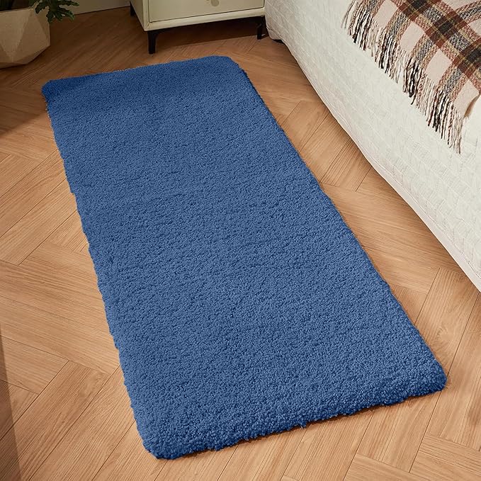 Blue rectangular bathmat on wooden floor beside bed in cozy bedroom setting