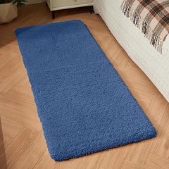 Blue rectangular bathmat on wooden floor beside bed in cozy bedroom setting