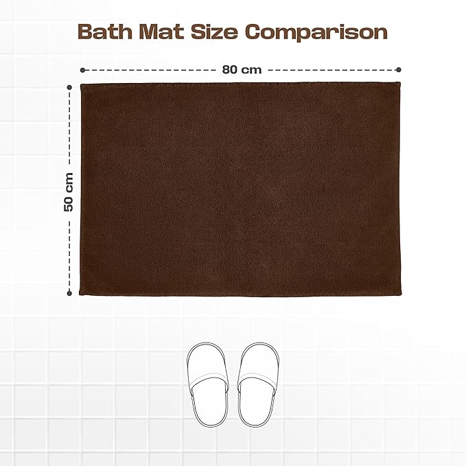 Brown bath mat 50x80 cm on white tiles with size comparison to slippers.