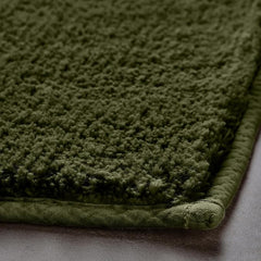 Close-up of a green textured bathmat with soft, plush fibers on a bathroom floor