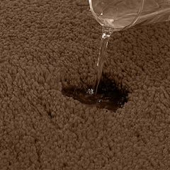 Water being poured on a brown absorbent bathmat to show absorbency