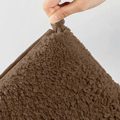 Hand holding a soft brown sherpa bathmat with a textured surface
