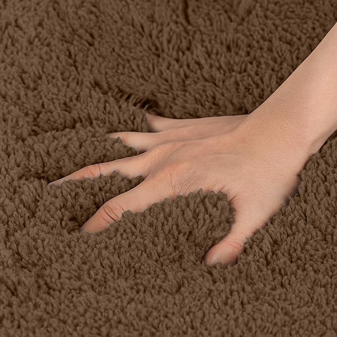 Hand pressing down on soft, brown, fluffy bathmat for bathroom decor