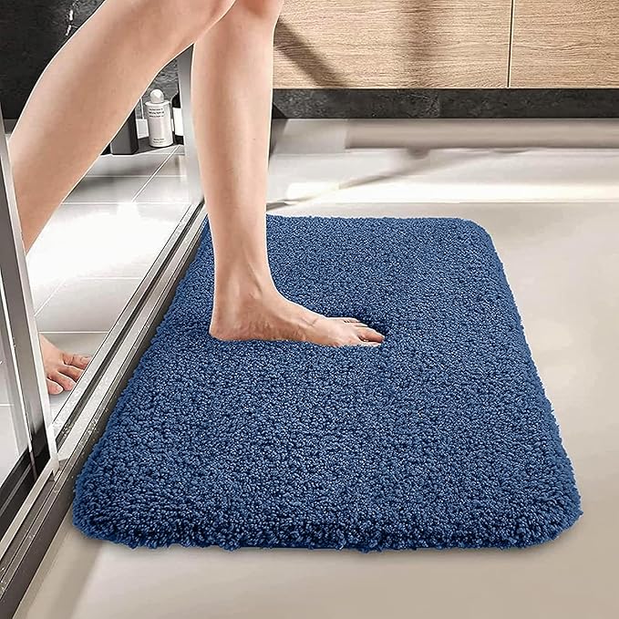 Person stepping onto a blue bathmat outside a shower in a modern bathroom