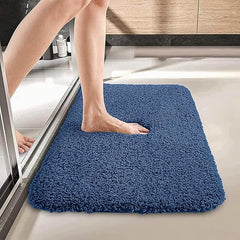 Person stepping onto a blue bathmat outside a shower in a modern bathroom