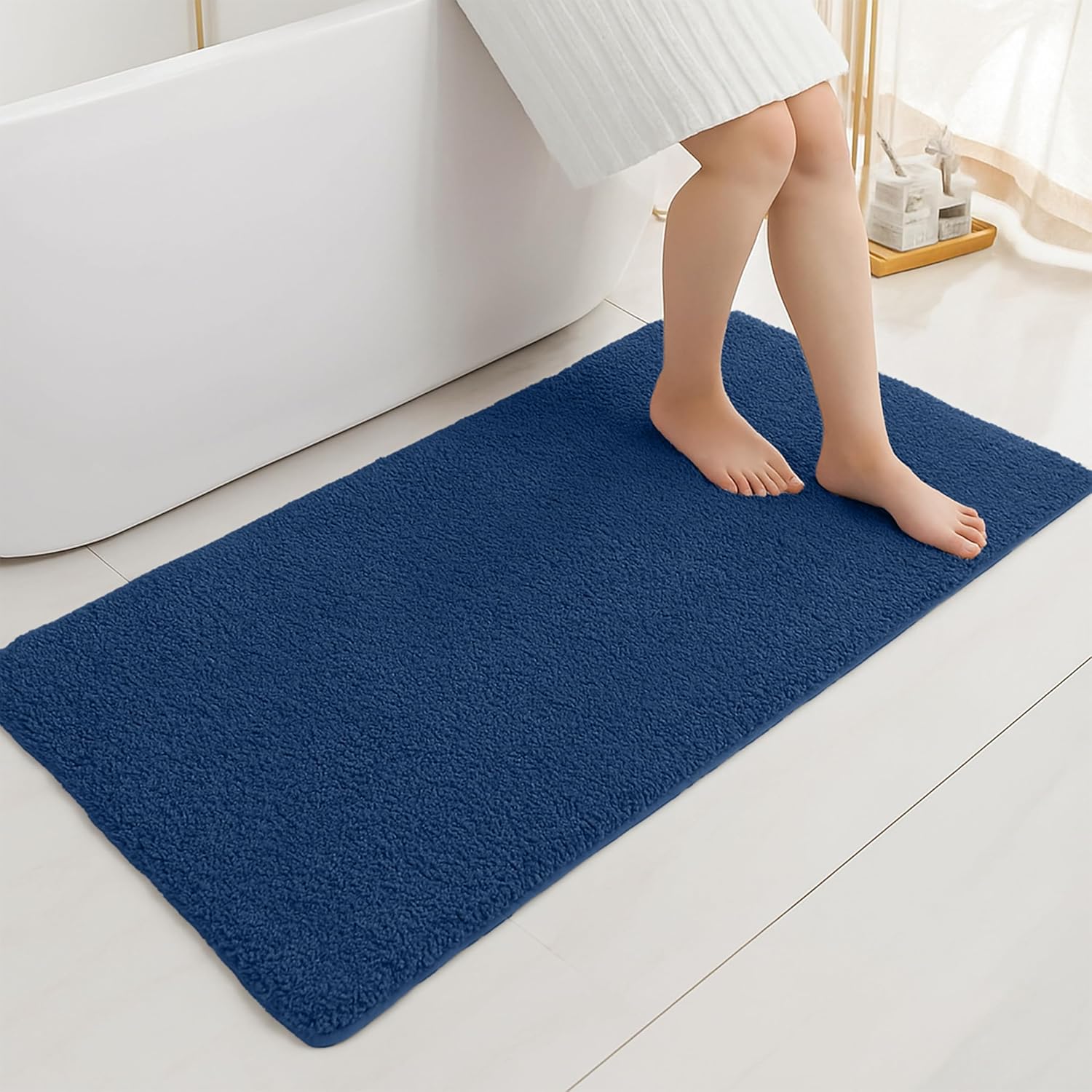 Blue bathmat in modern bathroom with person stepping out of bathtub onto soft mat