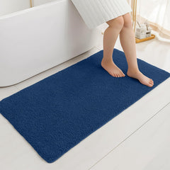 Blue bathmat in modern bathroom with person stepping out of bathtub onto soft mat