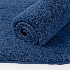 Fluffy dark blue bathmat rolled up on a white background, soft bathroom rug