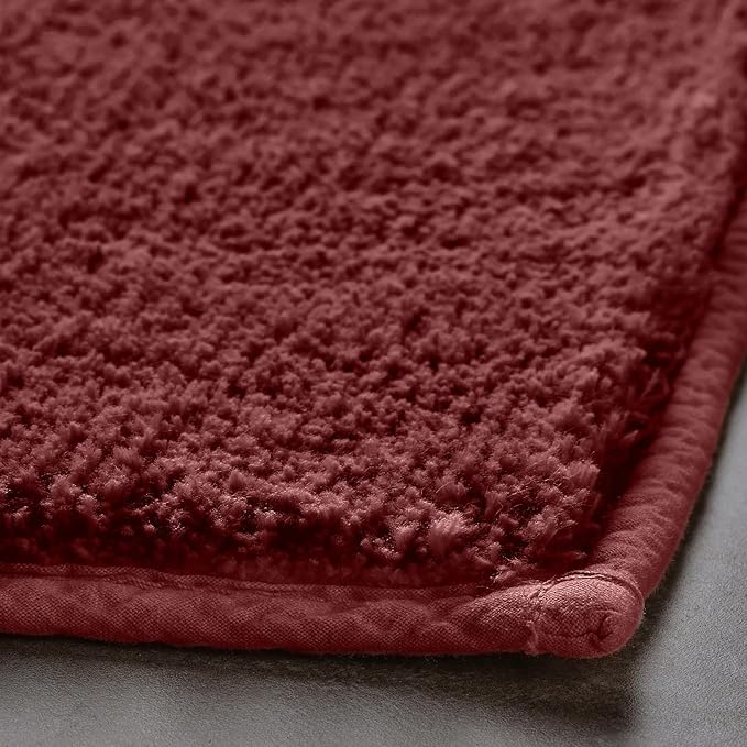 Close-up of a soft maroon bathmat with textured surface on a bathroom floor