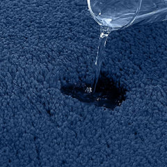 Water being poured onto a blue absorbent bathmat to show water resistance