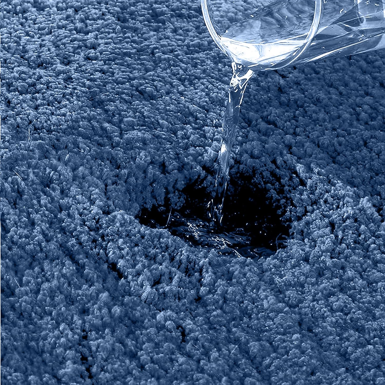 Water being poured onto an absorbent blue bathmat, demonstrating water resistance