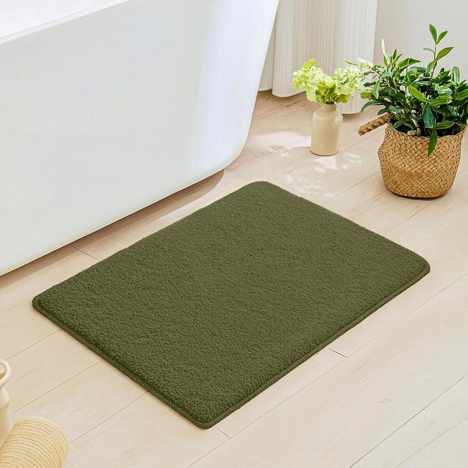 Green bathmat on light bathroom floor beside white bathtub and indoor plants