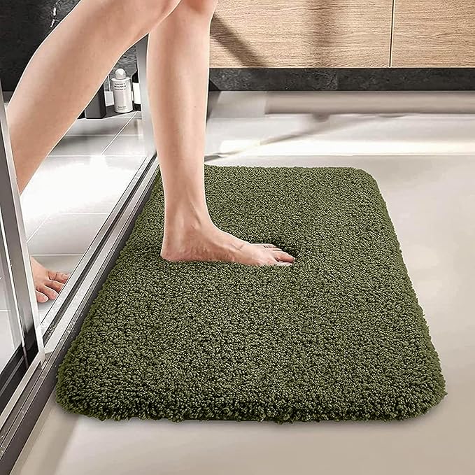 Green bathmat with soft texture placed outside a shower with a foot stepping on it