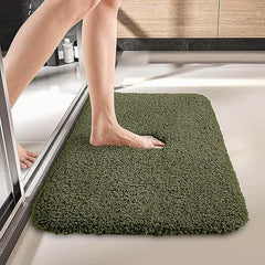 Green bathmat with soft texture placed outside a shower with a foot stepping on it