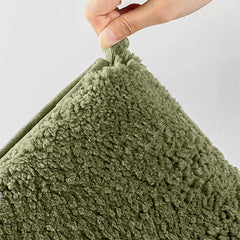 Hand holding soft green textured bathmat or pillow corner, close-up view